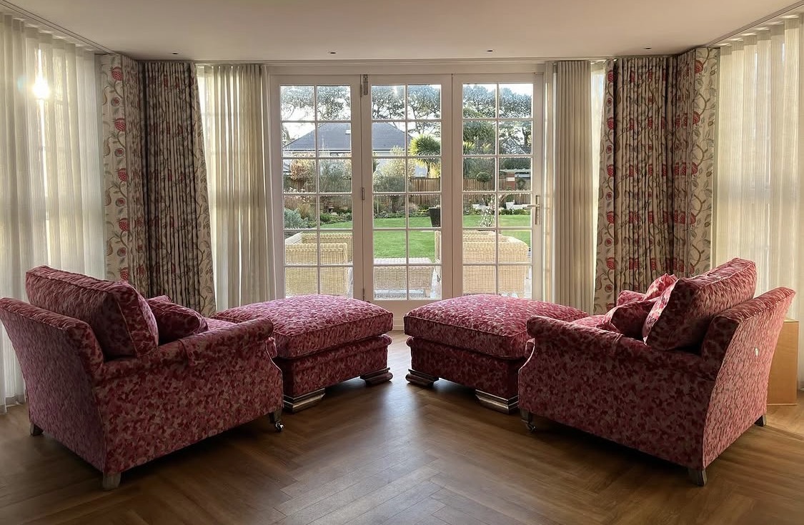 Two upholstered chairs with matching footstools in a bright living room